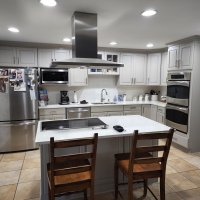 A spacious, open-concept kitchen with white cabinets, stainless steel appliances, and a large island with seating.