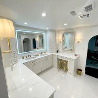 A luxurious master bathroom with a double vanity, large mirrors, sconce lighting, and a black freestanding tub