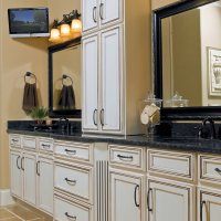 A bathroom vanity with a double sink, white cabinets, and a large framed mirror.