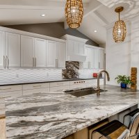 Beautiful contemporary kitchen with white cabinetry and 2 different styles of countertop - quartz countertop and marble countertop. White cabinets, marble island, quartz countertops