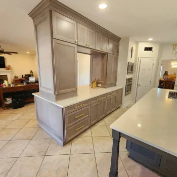 Large bar cabinet peninsula in light gray stain with cabinetry and crown going to the ceiling