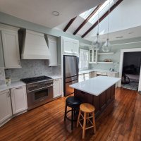 White painted kitchen cabinetry with stained hardwood floors, shiplap chimney hood, stained island cabinetry and white quartz countertops