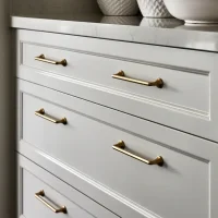 Close-up view of white cabinet drawers with brass hardware and fixtures