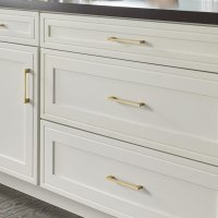 Version 1.0.0 An image showing a kitchen cabinet with white drawers and gold hardware.