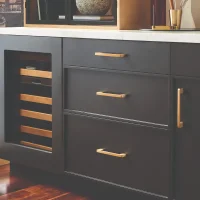 An image showing a kitchen cabinet with dark gray drawers and gold hardware.