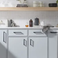 An image showing a kitchen cabinet with dark gray drawers and black hardware, including a wine cooler.