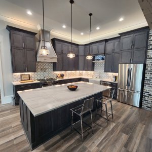 High-end Northshore style with Mandeville quartzite countertops in St. Tammany Parish. This breathtaking island utilizes a near full-size slab of luxury Sea Pearl Quartzite. The large format highlights the stone's soft, seafoam-tinted gray veining, creating an imposing and elegant centerpiece. Mandeville quartzite countertops featuring a near full-slab Sea Pearl Quartzite kitchen island with dense natural veining in St. Tammany Parish.